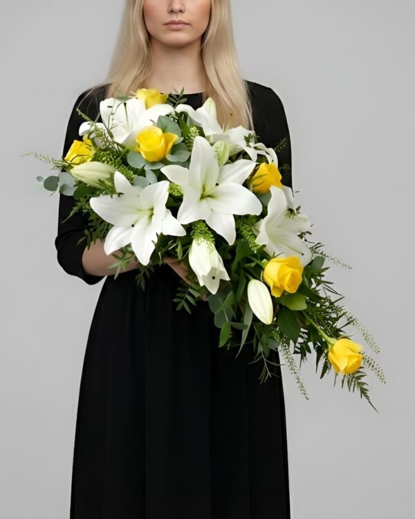 Respectful Lily and Rose Casket Spray by The London Bloom featuring white lilies, yellow roses, and seasonal greenery.