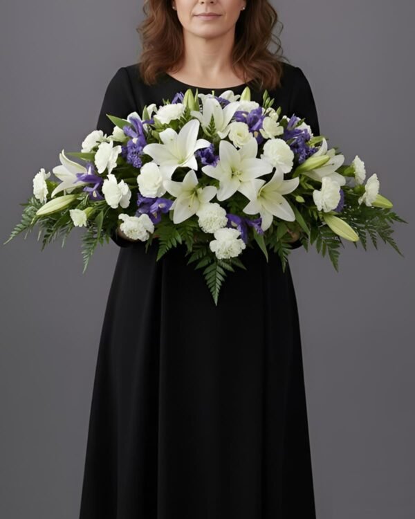 Respectful Carnation and Lily Casket Spray by The London Bloom featuring white carnations, elegant white lilies, and vibrant blue irises.